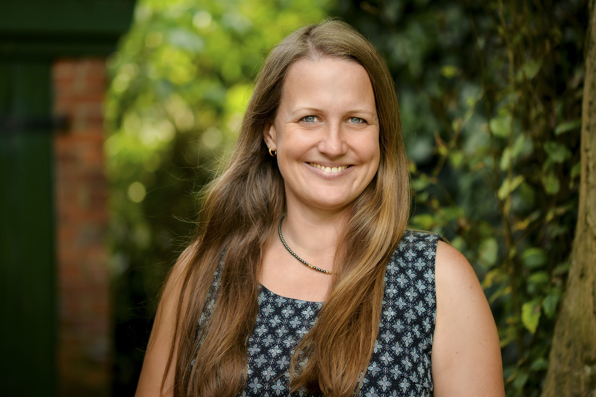 Eine Frau mit langen Haaren und Sommerkleid lächelt